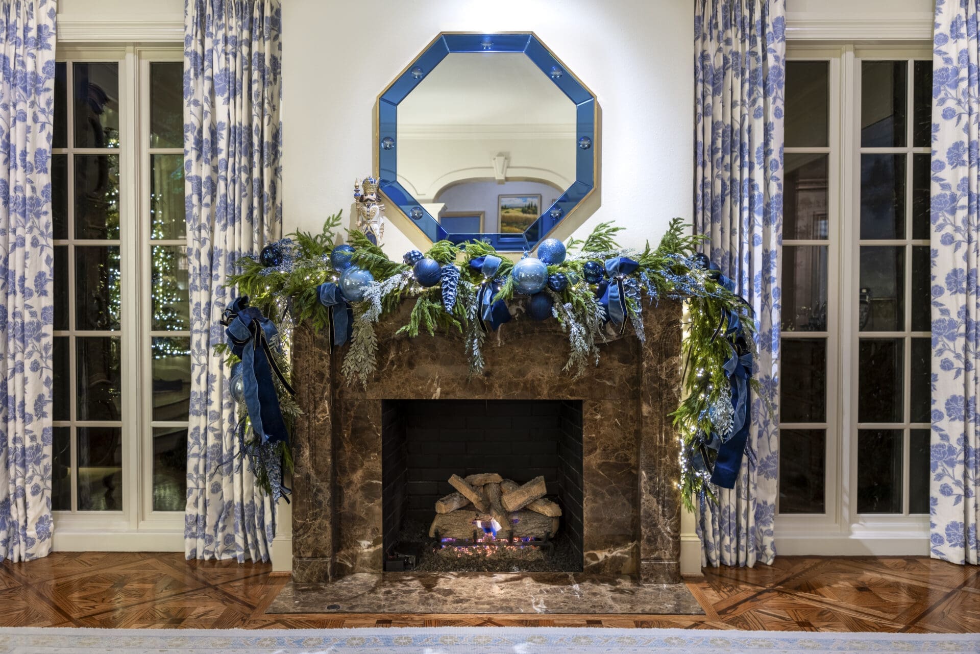 Luxury 2026 Christmas mantel decor trends featuring warm lit garlands by Baker Design Group.